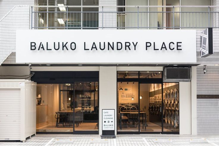 the entrance to an empty laundry place in front of a white building with black lettering on it