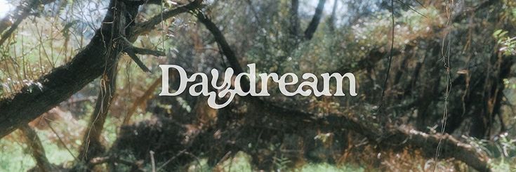 the word daydream is written in white letters on a background of trees and grass