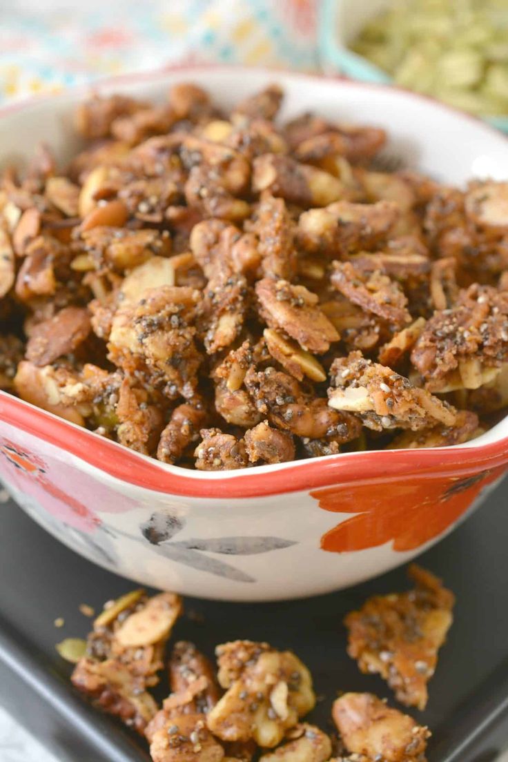 a bowl filled with nuts sitting on top of a black tray next to other food