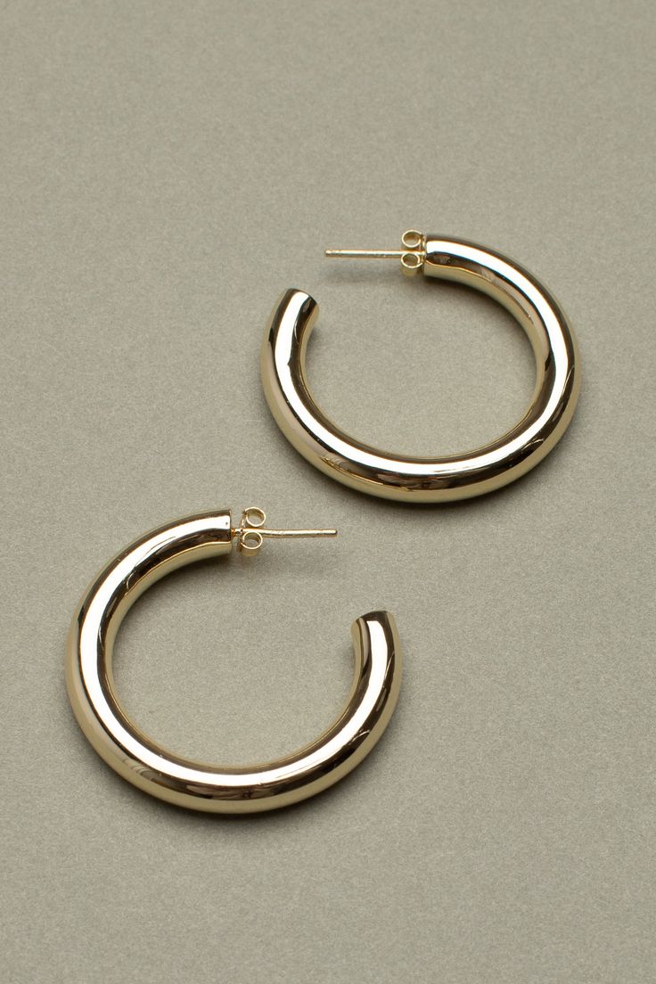 Oversized hoops, handmade from recycled brass and plated in 14K gold. Hypoallergenic posts with engraved butterfly backings. Jewelry Care: The oils from your skin transfer to the metal and need to be washed off periodically. The easiest way to clean your earrings is to wash with mild soap and wipe with soft, dry cloth. Store when not in use. Handmade from recycled brass 14K Gold Plated Hypoallergenic posts and logo-engraved backings Approximately 2" inches in diameter 5.2mm thick Tarnish Resistant Rounded Earrings For Everyday, Gold Tarnish-resistant Rounded Earrings, Gold Rounded Earrings For Everyday, Yellow Gold Rounded Earrings For Gift, Yellow Gold Earrings Gift, Classic Brass Hoop Earrings As Gift, Gold Polished Finish Earrings, Gold Rounded Earrings With Polished Finish, Everyday Brass Earrings With Polished Finish