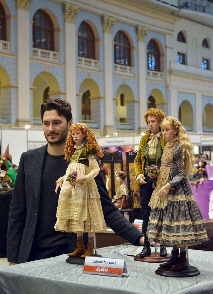 a man standing next to a table with dolls on it