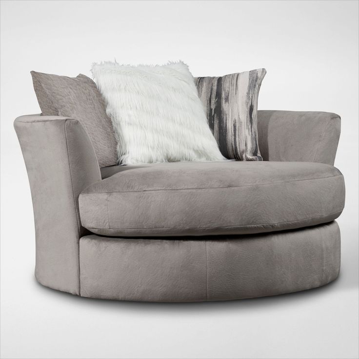 a large round chair with pillows on it's back and side rests in front of a white wall