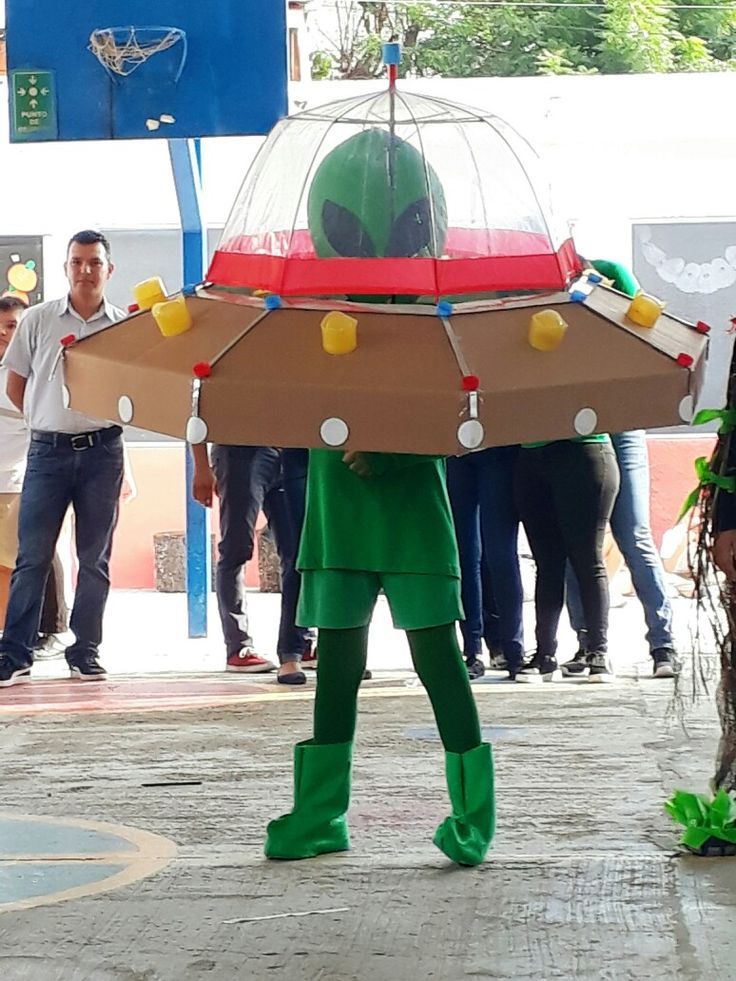 a man in green is holding a birdcage with lights on it's head