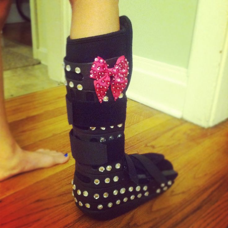 a person's feet wearing black boots with pink bows