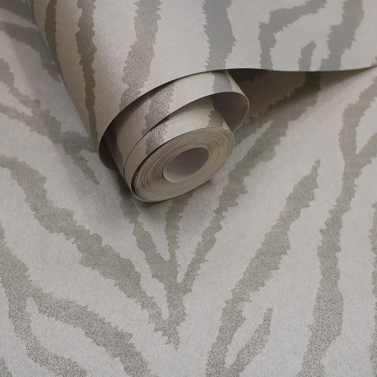 a roll of silver metallic foil paper on top of a white and gray wallpaper