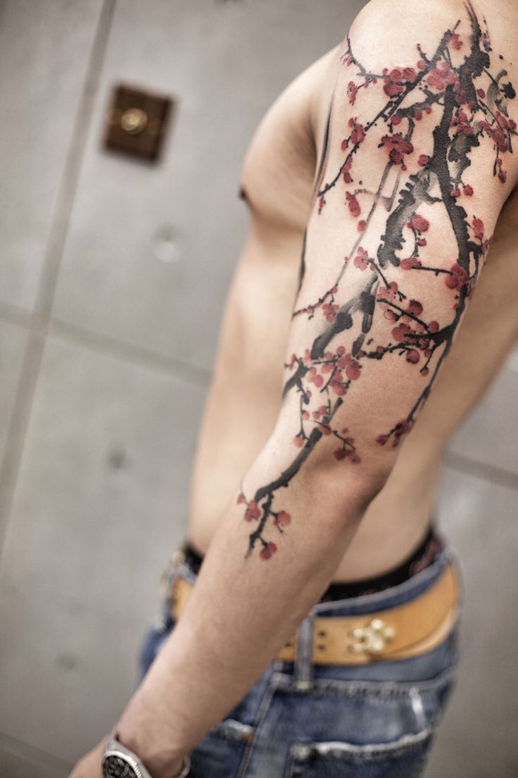 a man with a cherry blossom tattoo on his left arm and half - sleeved shirt