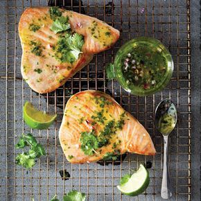 two fish fillets on a cooling rack with limes and cilantro sauce