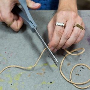 a woman is working on something with scissors and thread in the process of making it