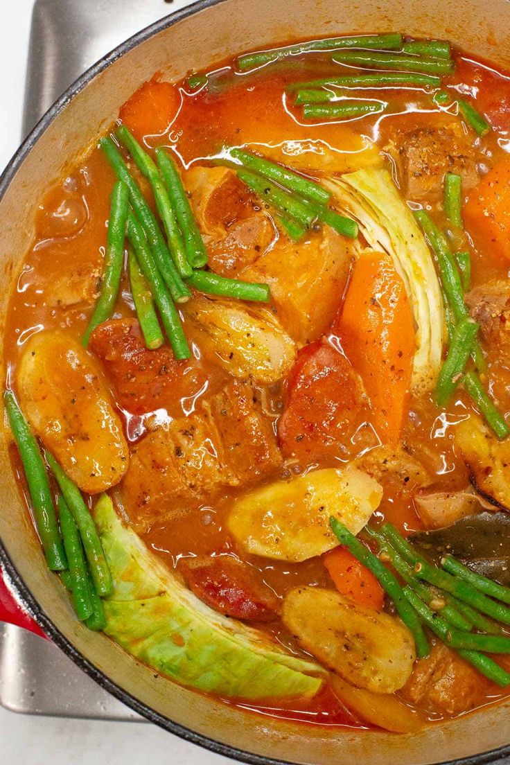 a pot filled with vegetables and meat on top of a stove