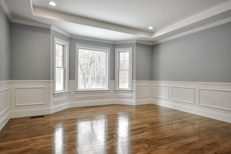 an empty room with hard wood floors and gray walls