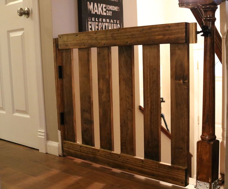 a wooden gate in the corner of a room next to a white door and stairs