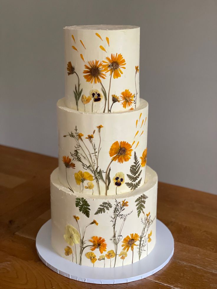 a three tiered cake decorated with flowers on a wooden table topper and white plate