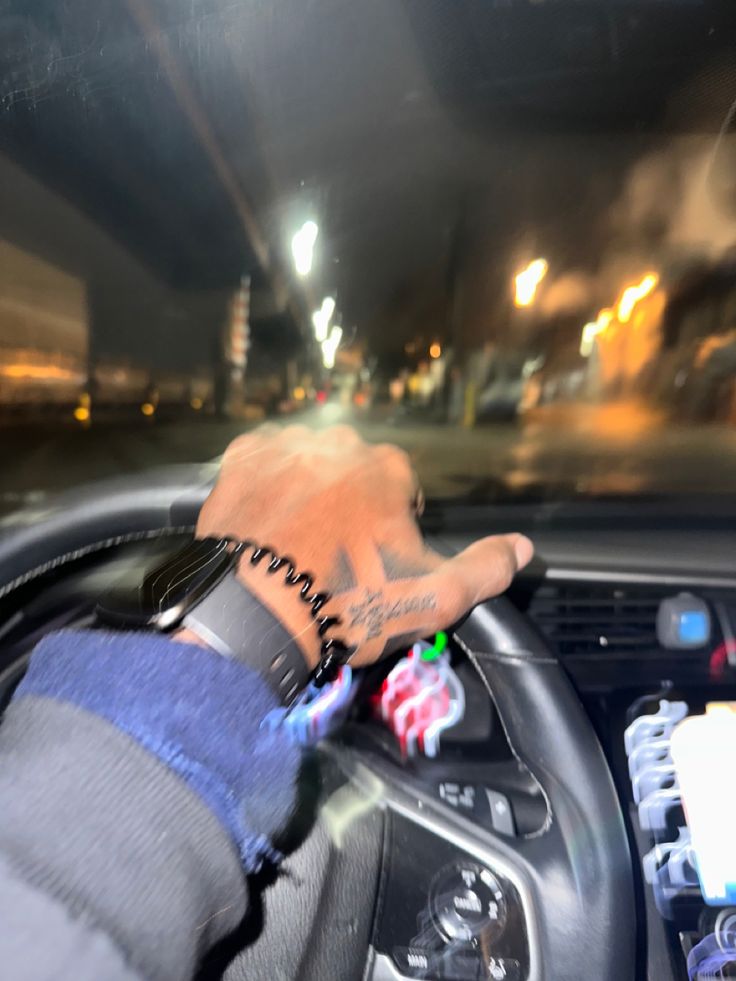 a man driving a car at night with his hand on the steering wheel and writing on the dashboard