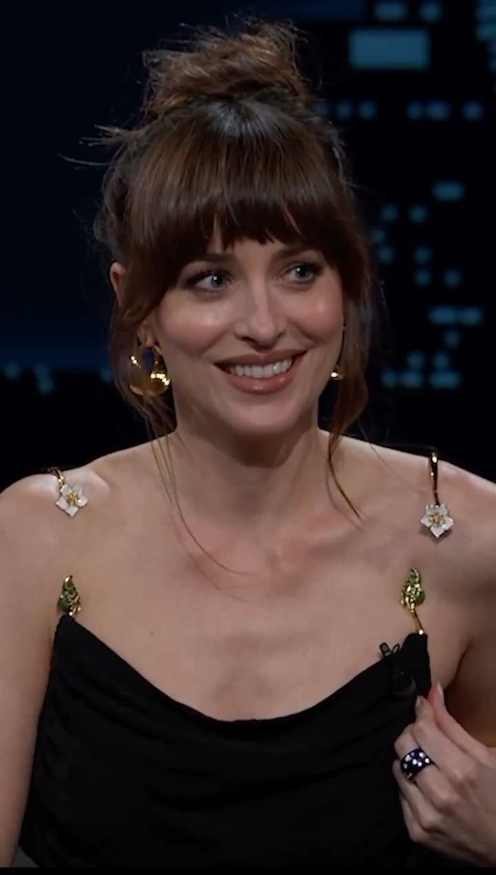 a woman in a black dress is smiling and wearing large gold earring earrings on her left hand