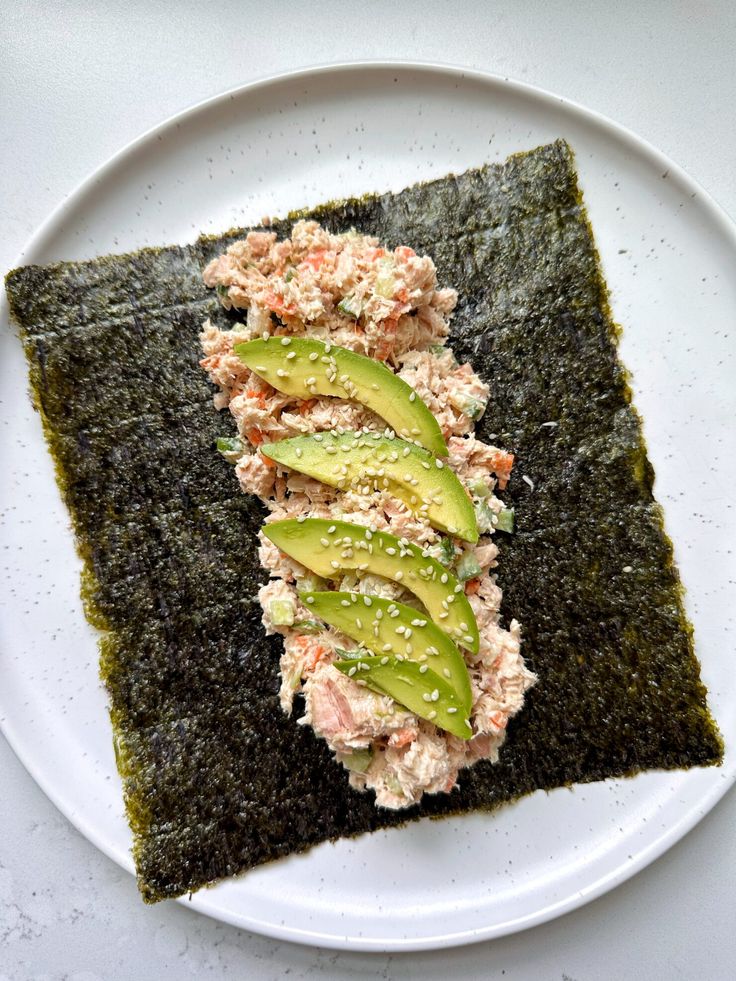 a white plate topped with sushi and avocado on top of green sauce