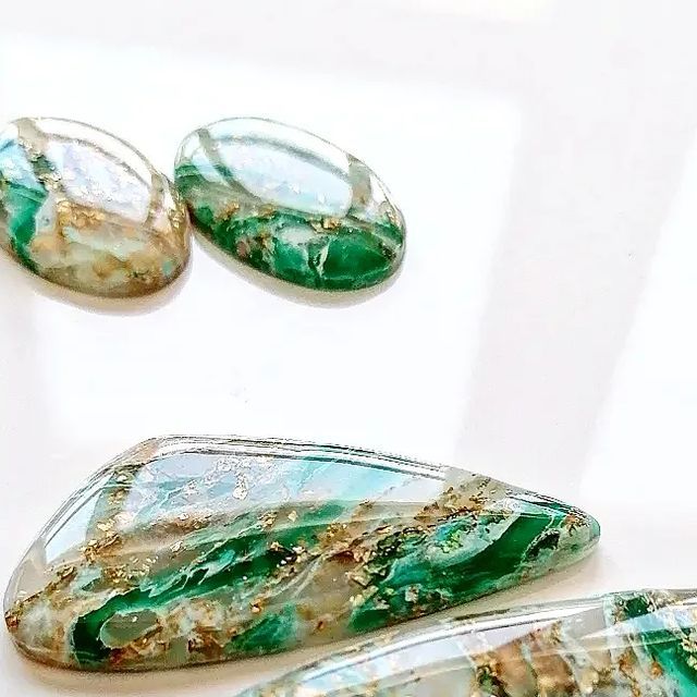 three pieces of green and white glass sitting on top of a table next to each other