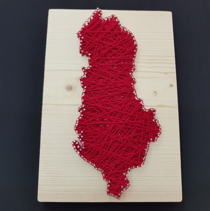 a string art piece is displayed on a wooden board with red thread in the shape of a state