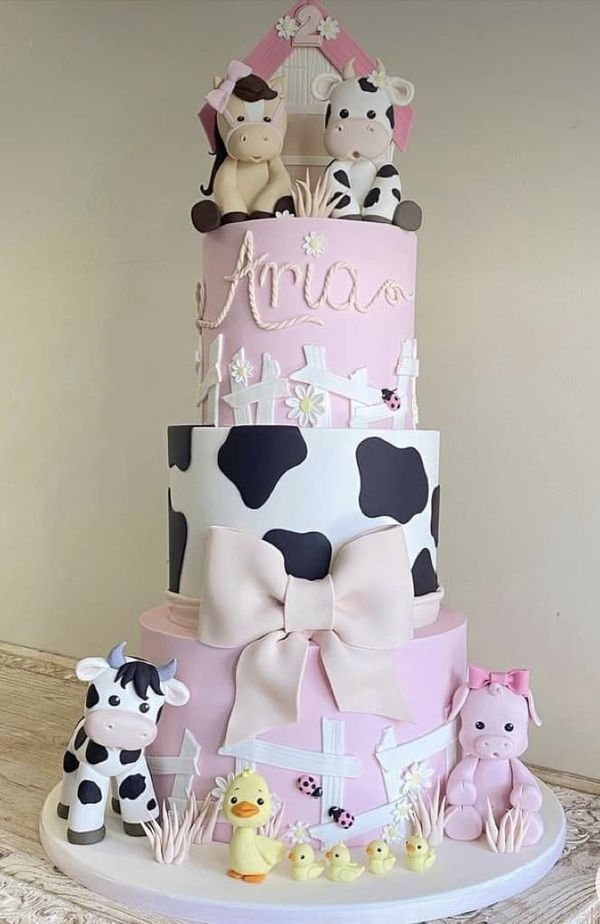 a three tiered cake decorated with farm animals and baby's name on top