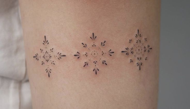 a woman's leg with small tattoos on the legs and one has an image of snowflakes