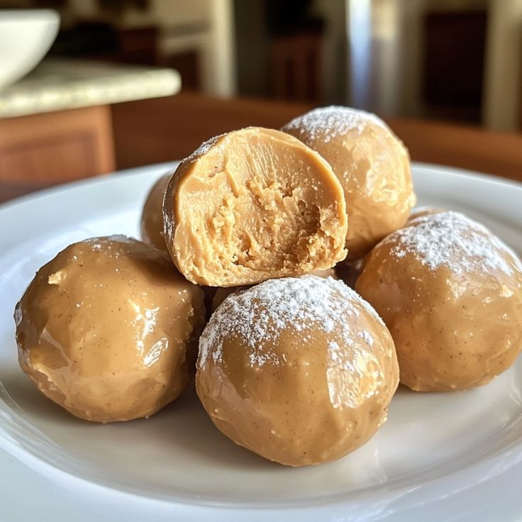 four donuts on a white plate with powdered sugar and peanut butter in the middle