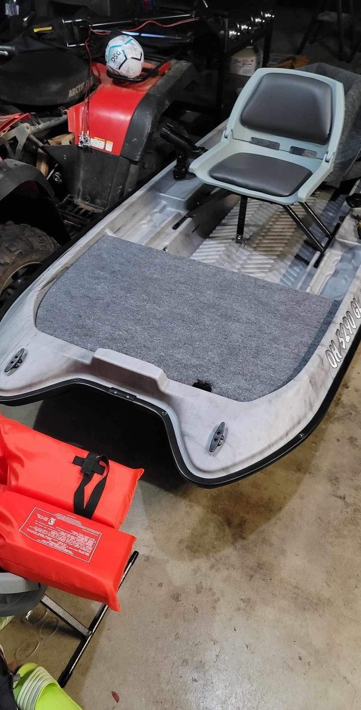 an inflatable boat sits on the ground next to some other vehicles and tools