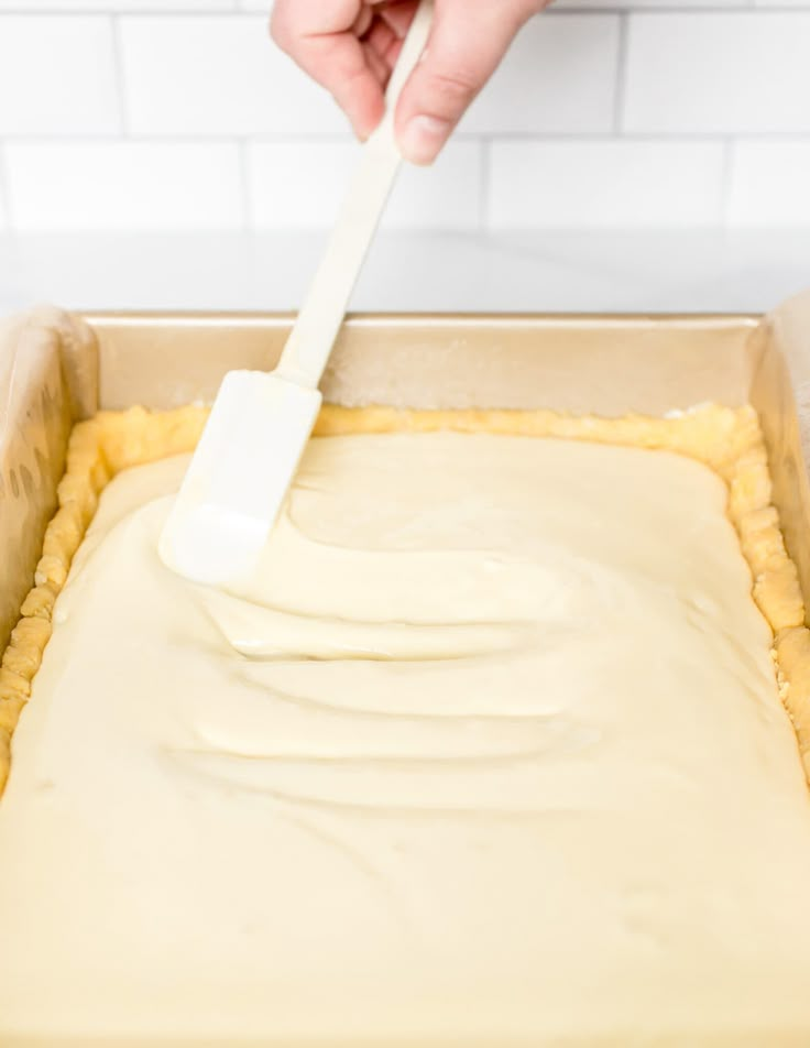 a person spreading icing on top of a cake in a pan