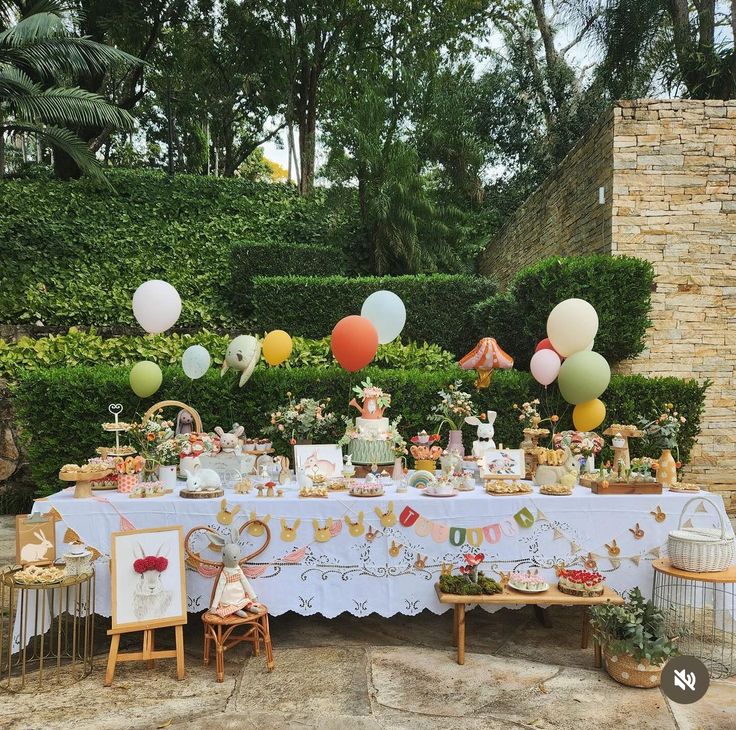 a table set up for a tea party with balloons in the air and decorations on it