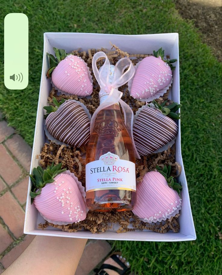 a box filled with chocolate covered strawberries next to a bottle of wine