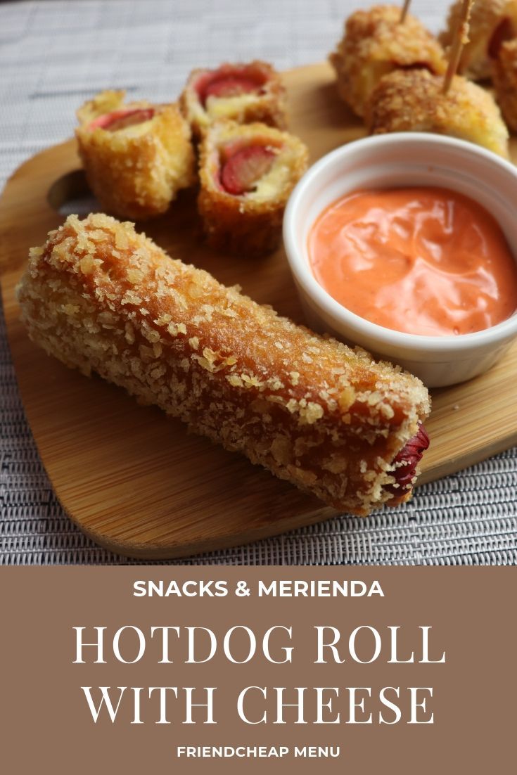 hotdog roll with cheese and dipping sauce on a wooden platter next to a bowl of dip