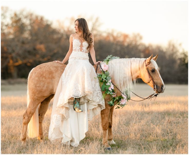 a woman in a wedding dress is standing next to a horse with flowers on it