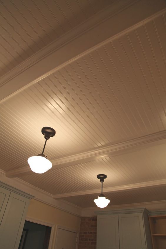 two lights are hanging from the ceiling in an empty room with white cabinets and cupboards