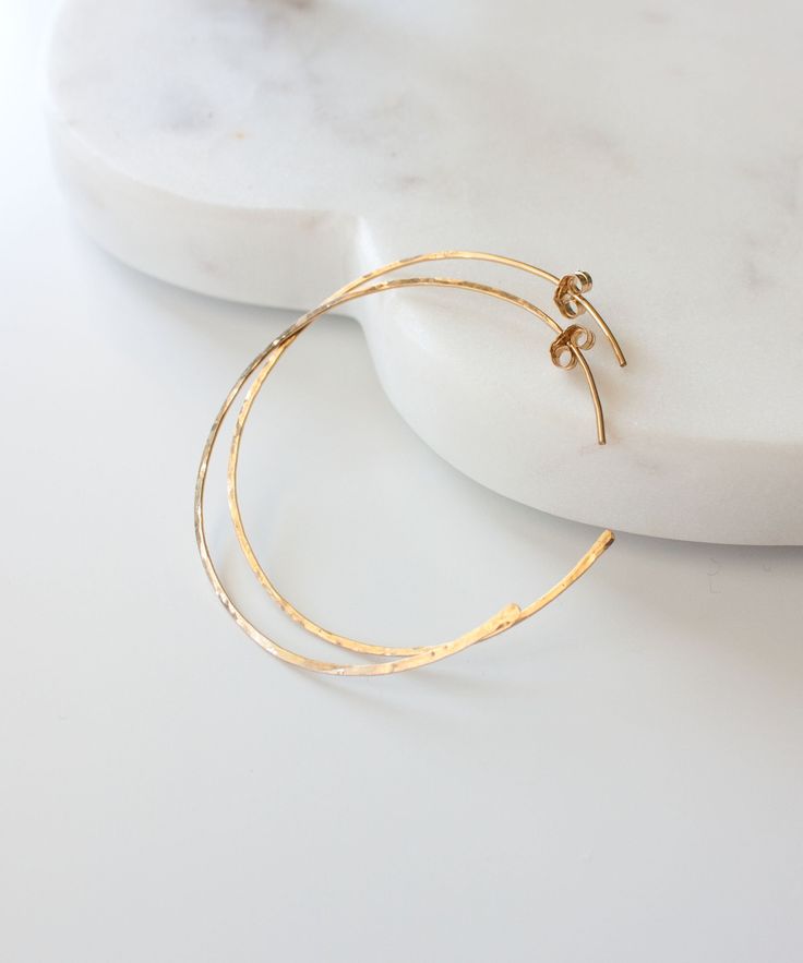 Our Maya Open Hoop earrings are weightless and versatile for your daily style. Handcrafted from 14k Gold Fill, the hammered texture reflects light from all sides. Easy open hoop design adds a modern update to your everyday hoop.Choose from 1.75" or 2" sizing + Thin 20 gauge style with gold earring backs or Thicker 18 gauge style with clear earring backs.MATERIALS 14k Gold Filled MEASUREMENTS1.75 - 2" drop from ear ORIGIN Handcrafted in Florida STYLEMAYE01 | MAYE02FREE Standard Shipping for all U Sides Easy, Boho Hoop Earrings, Clear Earrings, Open Hoop Earrings, Gold Filled Hoops, Hoop Design, Hammered Gold, Beaded Hoop Earrings, Gold Earring