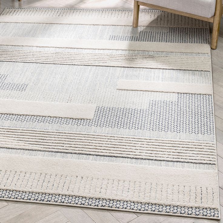 an area rug is shown with white and blue patterns on the floor, along with a beige chair