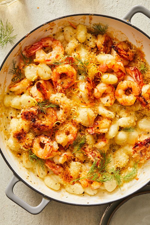 a pan filled with shrimp and cauliflower on top of a table