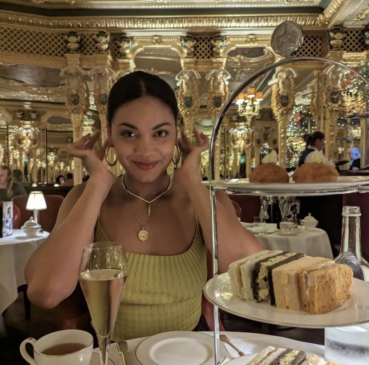 a woman sitting at a table with plates of food and drinks