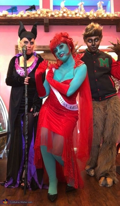 three people dressed up in costumes standing on a wooden floor with one holding a cane