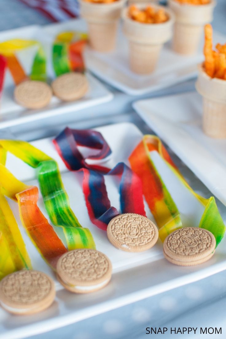 some snacks are sitting on trays next to cups and plates with candy in them