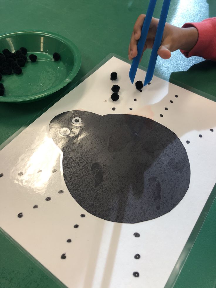 a child is playing with black beads on a white board