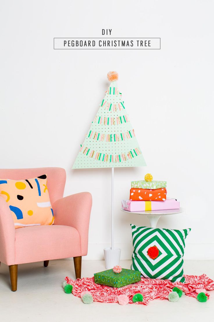 a pink chair sitting next to a christmas tree on top of a white wall in a living room