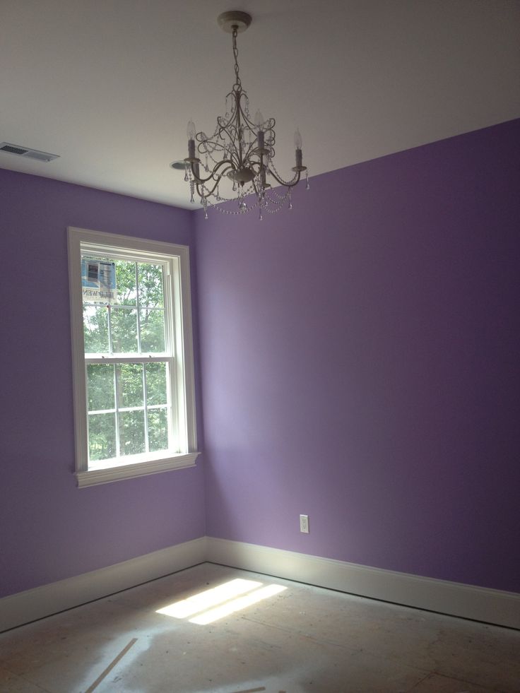 an empty room with purple walls and a chandelier hanging from the light fixture