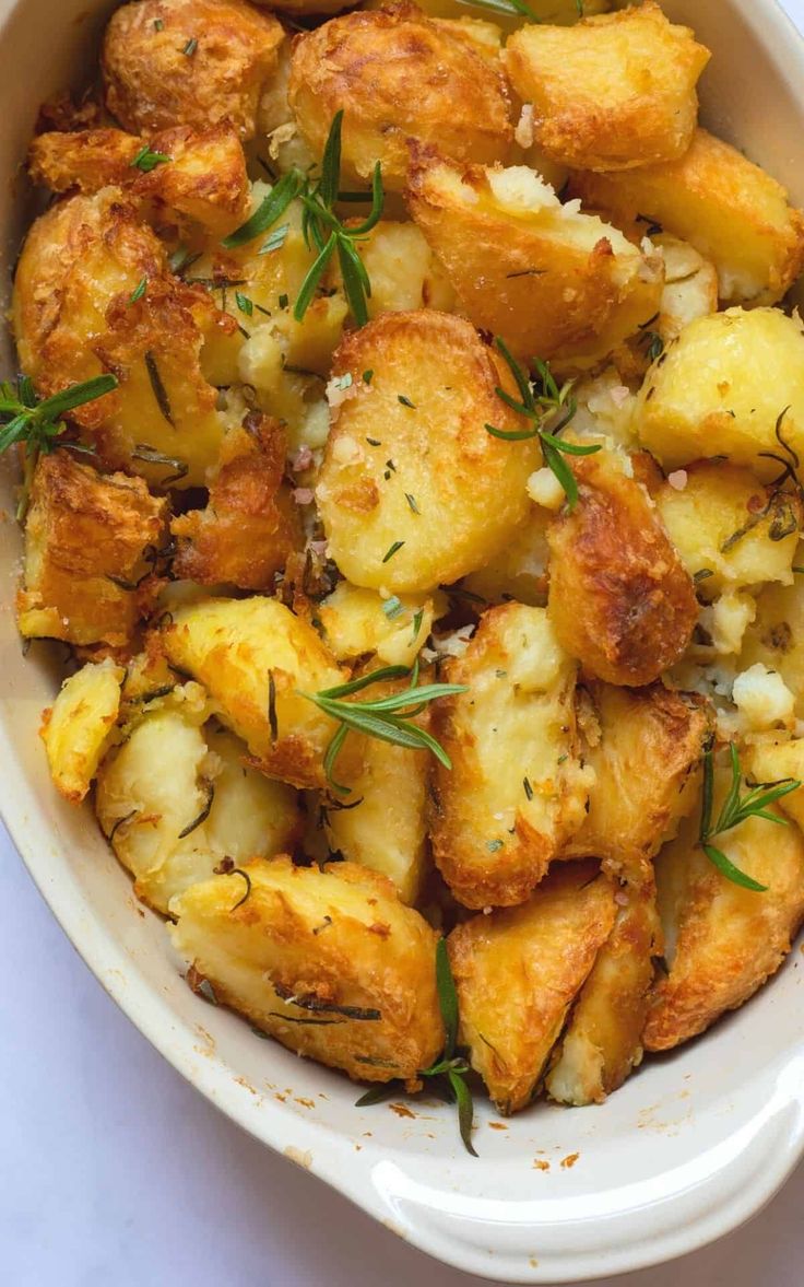 a white bowl filled with potatoes covered in herbs