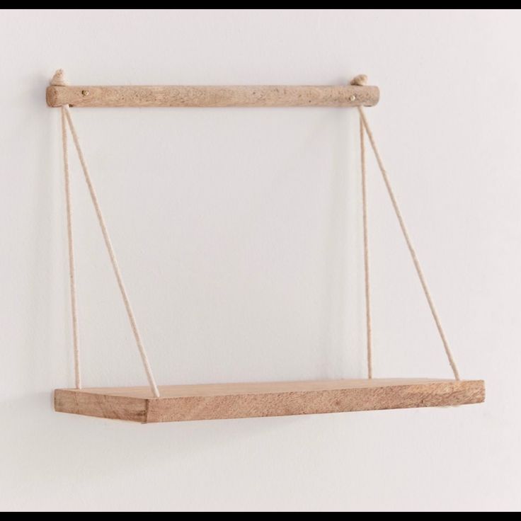 a wooden shelf hanging from the side of a wall with two strings attached to it