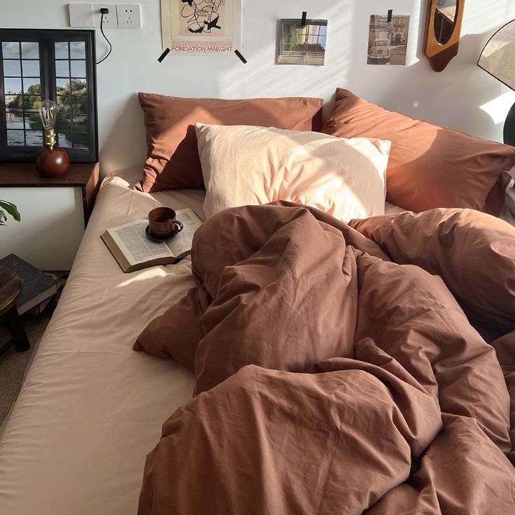 an unmade bed in a bedroom with brown sheets and pillows on top of it