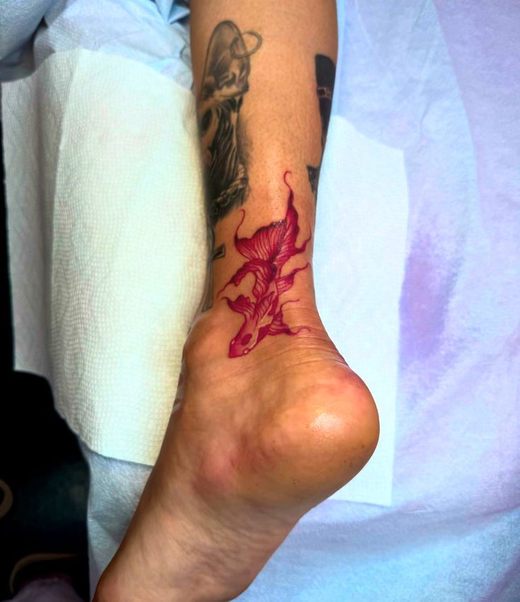 a person with a tattoo on their foot and the leg is covered in red ink