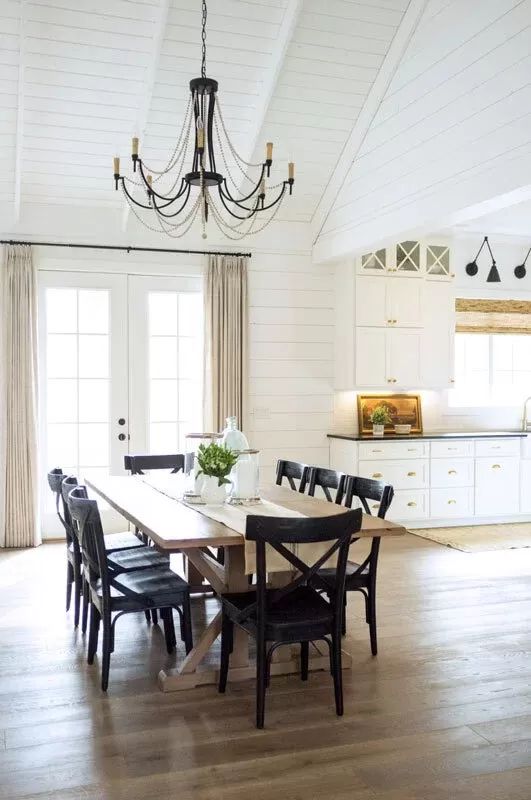 a dining room table with black chairs and a chandelier hanging from the ceiling