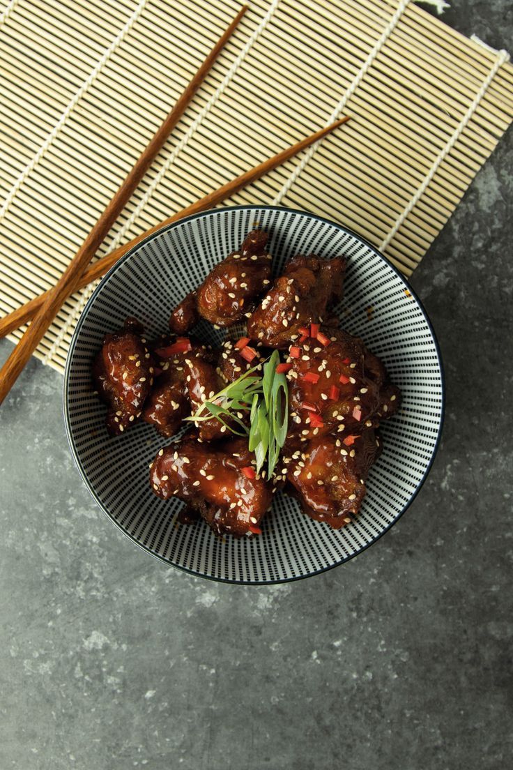 a bowl filled with meat next to chopsticks