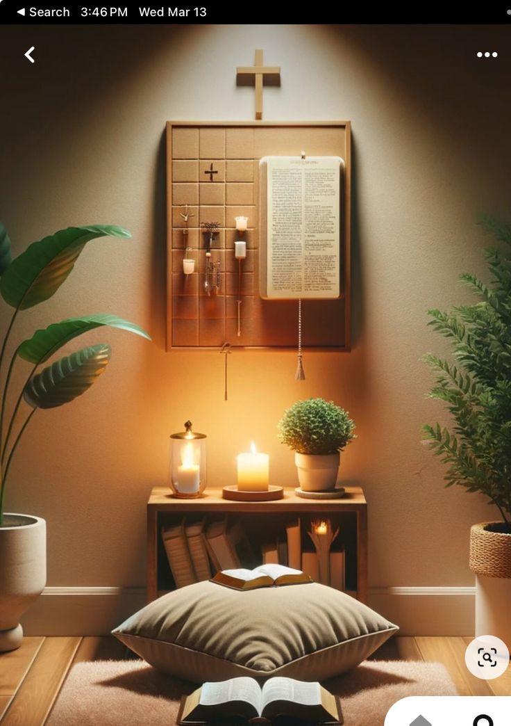 an open book sitting on top of a pillow next to a table with candles and potted plants