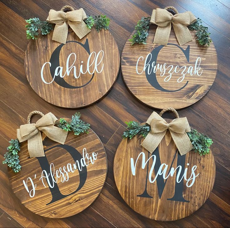 four wooden signs with bows on them that say names and are hanging on the floor