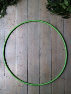 a green hula hoop sitting on top of a wooden floor next to greenery