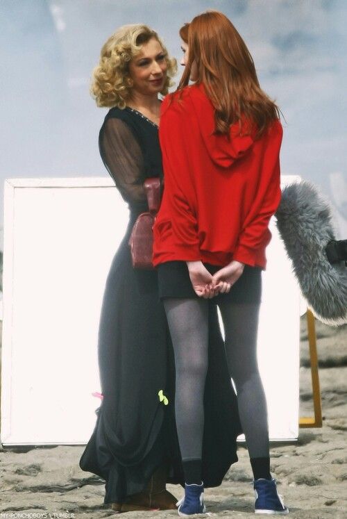 two women standing next to each other in front of a white board on the beach